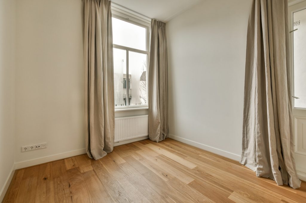 a living room with wood flooring and two windows