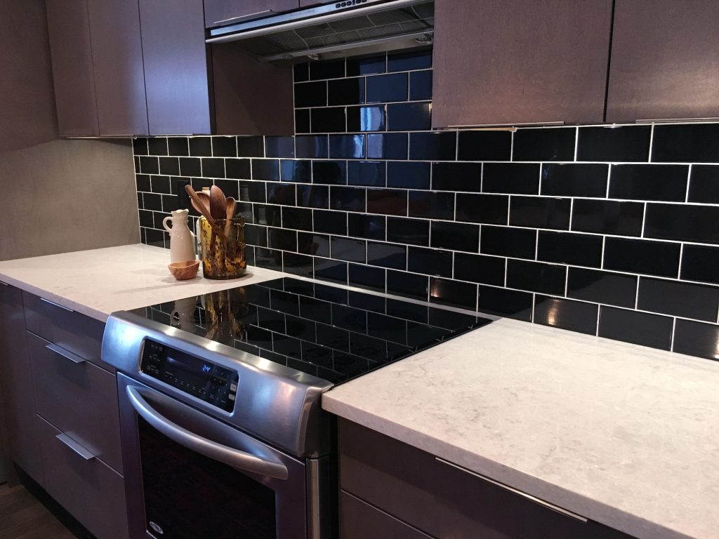 Modern kitchen in dark tones with black tiled wall