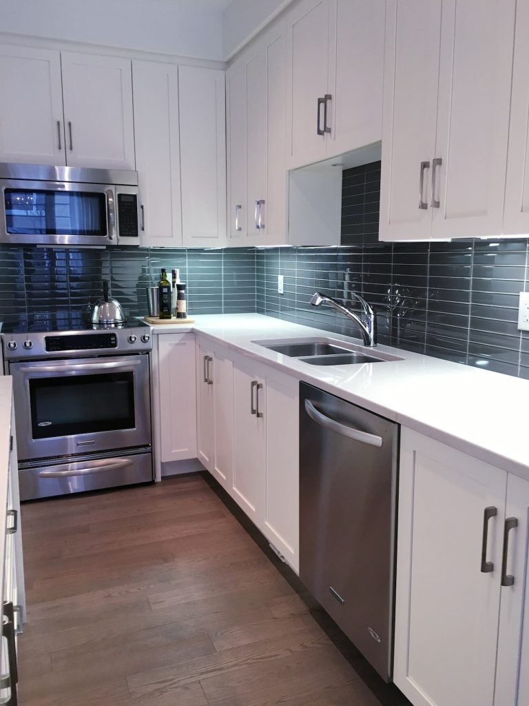 Modern kitchen with white furniture and glass tiles for backsplash