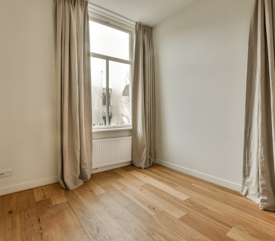 a living room with wood flooring and two windows